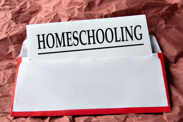 HOMESCHOOLING - word on a white sheet with an envelope background and crumpled red paper