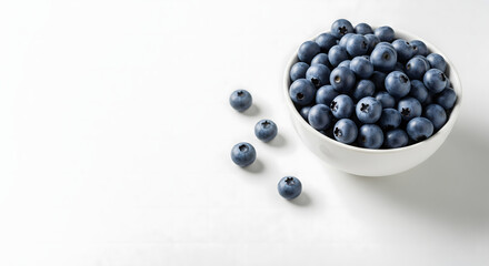 Fresh Blueberries in White Ceramic Bowl on Matte White Table – Top-Right Composition with Scattered Berries and Soft Natural Light, Ideal for Food Branding, Editorial Design, or Healthy Lifestyle Use
