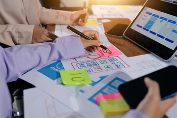 Close up ux developer and ui designer brainstorming about mobile app interface wireframe design on...
