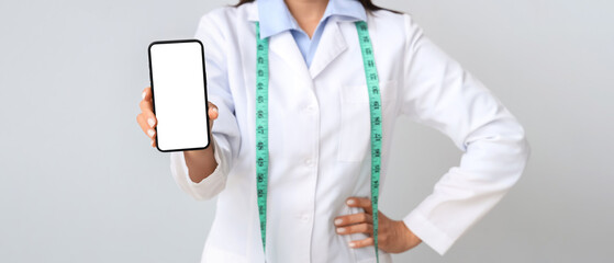 Female nutritionist with mobile phone on light background, closeup