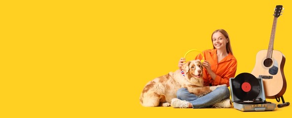 Young woman with Australian Shepherd dog, headphones and record player on yellow background with space for text