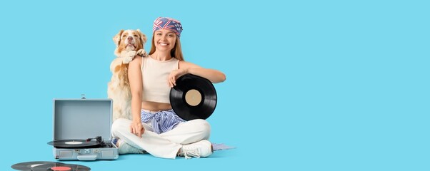 Young woman with vinyl disks, record player and Australian Shepherd dog sitting on blue background...