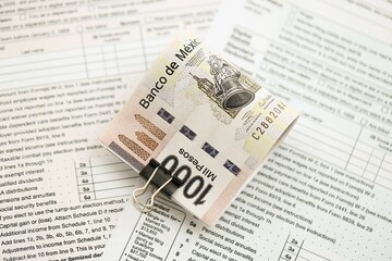 Mexican pesos money bills in big amount lies on table with tax forms close up