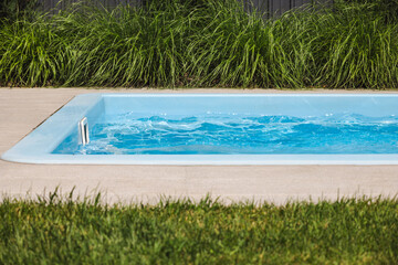 Obraz premium Empty backyard pool with active counter-current system generating waves near skimmer