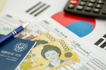 South Korean won money bills lies on table with pen, calculator, passport and tax forms