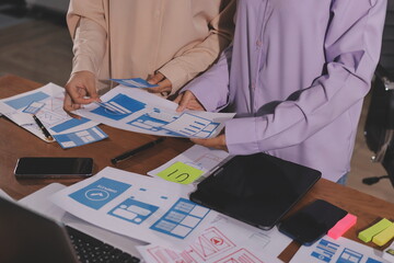 Close up ux developer and ui designer brainstorming about mobile app interface wireframe design on...