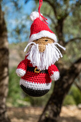 Papa Noel echo de ganchillo a mano de color rojo y barba blanca en el campo colgado de un olivo  
