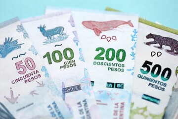 Argentine pesos money bills in big amount lies on teal color table close up