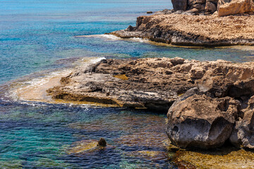 Rocky Coastline with Turquoise Water in Cyprus, Scenic view of a rugged rocky shoreline and crystal-clear turquoise sea on a sunny day. summer travel , hot summer