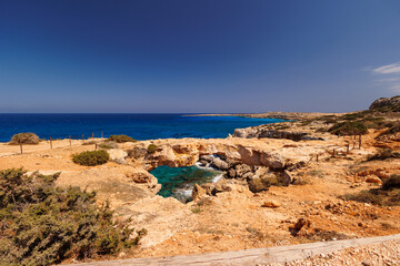 Rocky Mediterranean Coastline with Natural Sea Cave View  , Scenic view of rugged Cyprus coastline featuring natural rock formations, a sea cave.