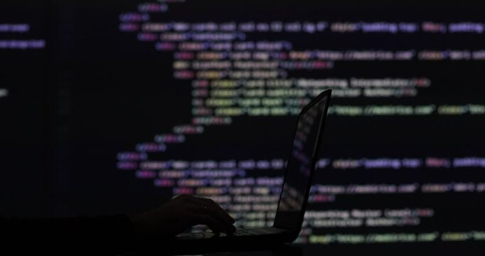 Hacker writing code cracking computer. Programming code in the background. Hacker attack, cybercrime, virus software, dark web, cyber security concept.