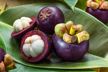 Obraz na płótnie Canvas Mangosteen fruits on green leaves close up.