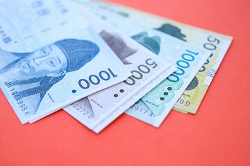 South Korean won money bills in big amount lies on red color table close up