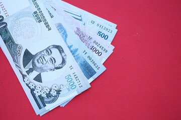 North Korean won money bills in big amount lies on red color table close up