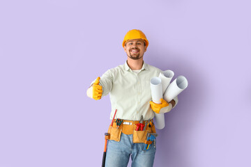 Male builder with house plans showing thumb-up on lilac background