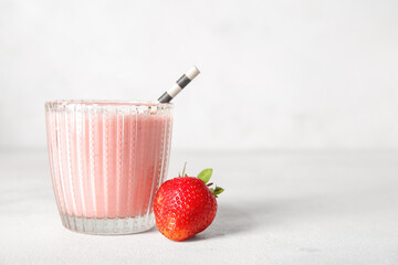 Glass of tasty strawberry smoothie on light background