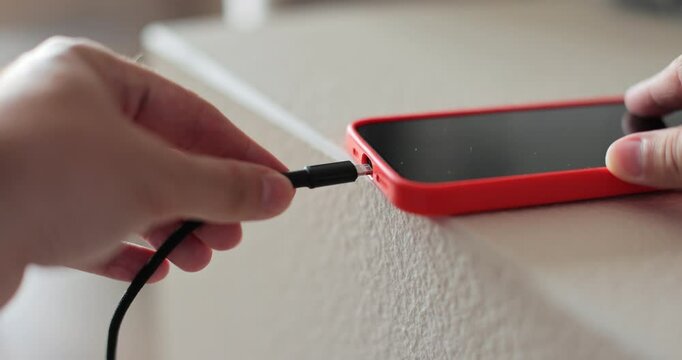 Closeup male hands connecting cable for transfer data. Unrecognizable man plugging cable into smartphone.