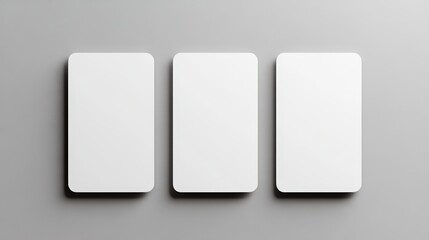 Three blank white cards with rounded corners are neatly arranged side by side on a smooth gray surface.