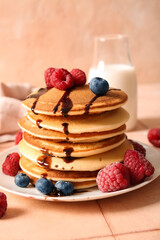 Plate of tasty pancakes with raspberries and blueberries on table