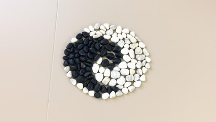 Minimalist yin-yang mosaic made from smooth pebbles. Harmony of contrasts emphasizes balance and tranquility. Perfect for zen and design themes.