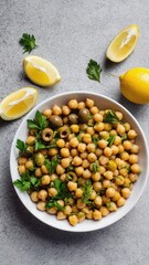 A bowl of chickpeas garnished with parsley and lemon slices. The dish is placed on a gray surface, showcasing a healthy and vibrant meal.