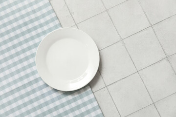 Clean plate and napkin on white tile background