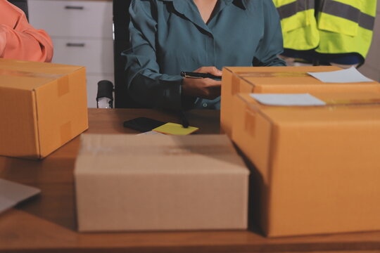 Startup SME small business entrepreneur of freelance Asian woman wearing apron using laptop and box to receive and review orders online to prepare to pack sell to customers, online sme business ideas.