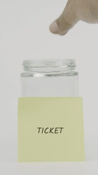 Ticket text or word on a yellow sticky note attached to a glass jar. A hand inserts a coin, symbolizing hidden goals or confidential savings. White background, vertical screen
