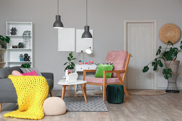Interior of stylish living room with grey sofa, armchair and glowing lamps at evening