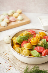 Bowl of boiled colorful dumplings with dill on white background
