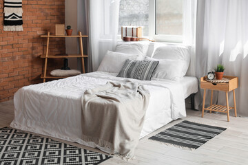 Interior of cozy bedroom with comfortable bed and alarm clock on bedside table