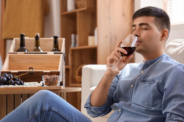 Young man with glass of red wine at home