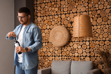 Sommelier opening bottle of wine with corkscrew in living room