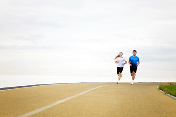 Morning joggers enjoy a refreshing run along the scenic waterfront path, surrounded by soft clouds...