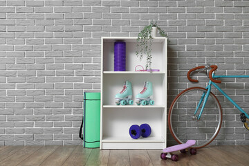 Shelf unit with sports equipment and bicycle near grey brick wall in room