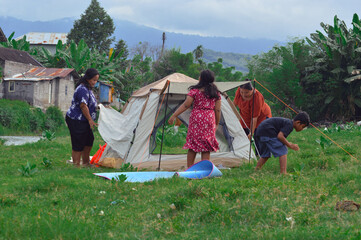 As the mothers finish setting up the tent, the girl watches and the boy continues his insect search...
