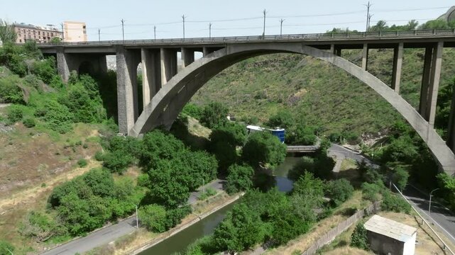 Kievyan Bridge on river Hrazdan with greenery and a road on a sunny clear day in Yerevan, Armenia.