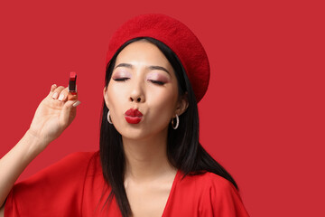 Beautiful Asian woman with lipstick on red background