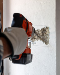 Carpenter electrician with demolition hammer prepares the cavity in the wall where to insert the...
