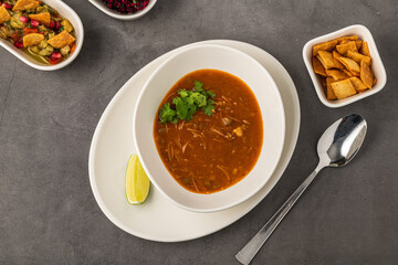 Spicy Mexican chicken soup with noodles, garnished with fresh cilantro and lime wedge