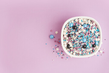 Bowl with colorful sprinkles on lilac background