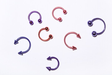 Set of colorful circular barbells for piercing on light background