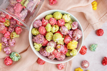 Bowl and glass with sweet colorful popcorn on white background