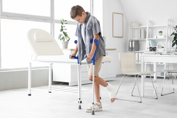 Injured little boy with crutches in clinic