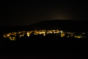 Night view of a small village illuminated by warm lights and surrounded by the dark countryside. Casas Altas in Rincón de Ademuz, Spain. Summer 2024