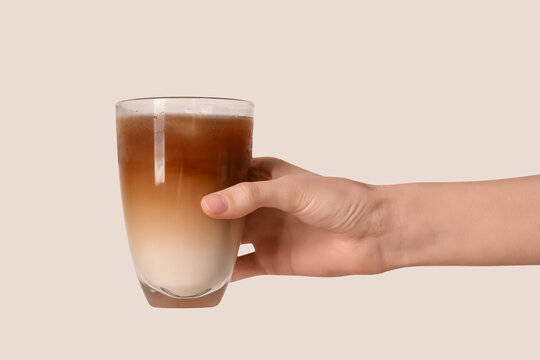 Female hand with glass of iced latte on white background