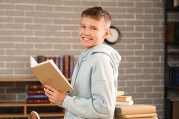 Teenage boy with book in library