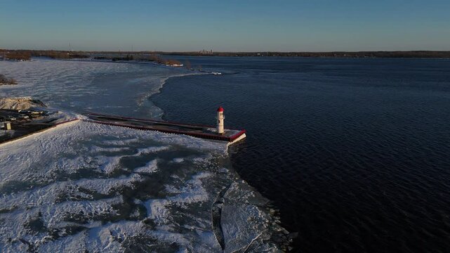Aerial orbit of lighthouse on icy waterfront in Winter in Montreal