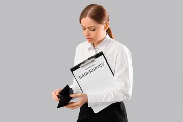 Businesswoman with empty wallet and petition to file for bankruptcy on light background