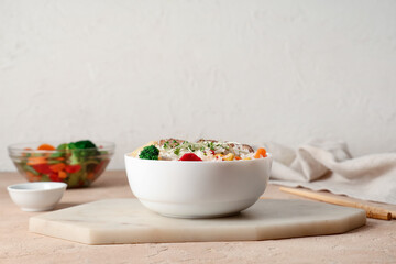 Board with bowl of tasty rice on color table